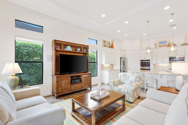 living room featuring light hardwood / wood-style flooring, ornamental molding, and a high ceiling