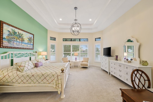 bedroom featuring a high ceiling, light colored carpet, an inviting chandelier, and a tray ceiling