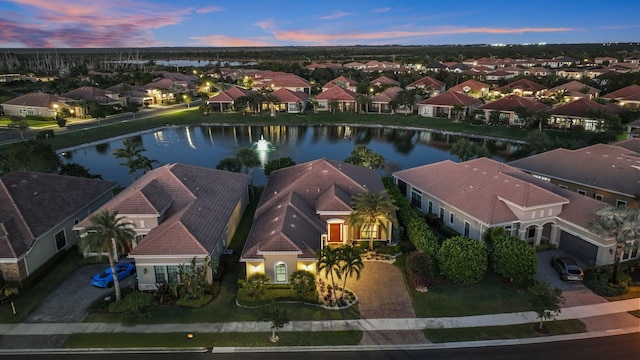 aerial view at dusk featuring a water view