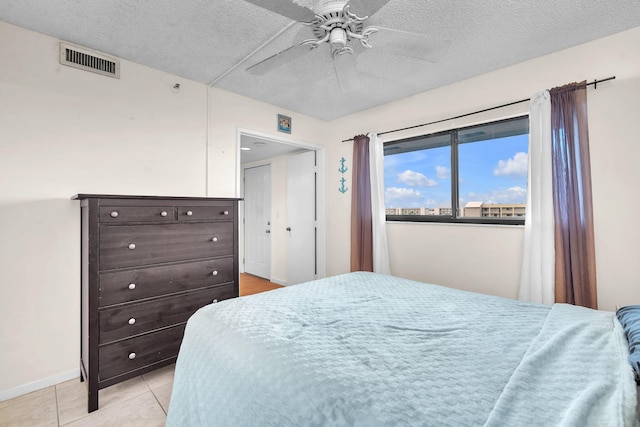 bedroom featuring ceiling fan, a textured ceiling, and light tile patterned floors