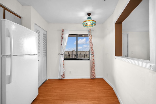 unfurnished dining area with baseboards and wood finished floors