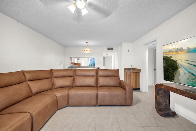 tiled living room featuring ceiling fan, sink, and a textured ceiling