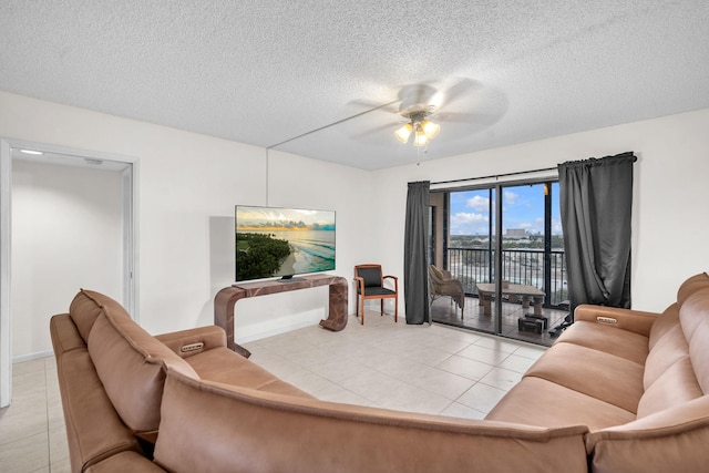 living room with ceiling fan, a textured ceiling, and light tile patterned floors