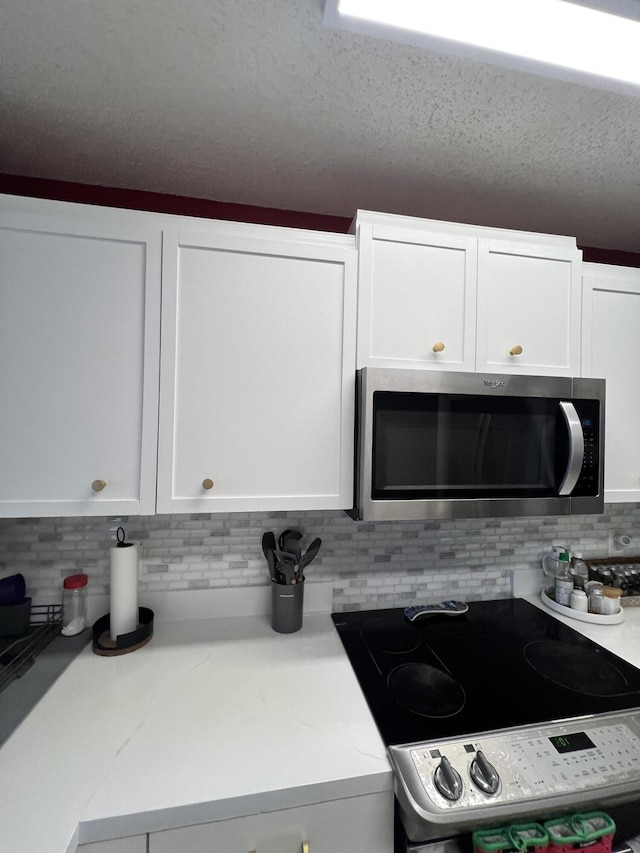 kitchen with white cabinets, tasteful backsplash, and electric range oven