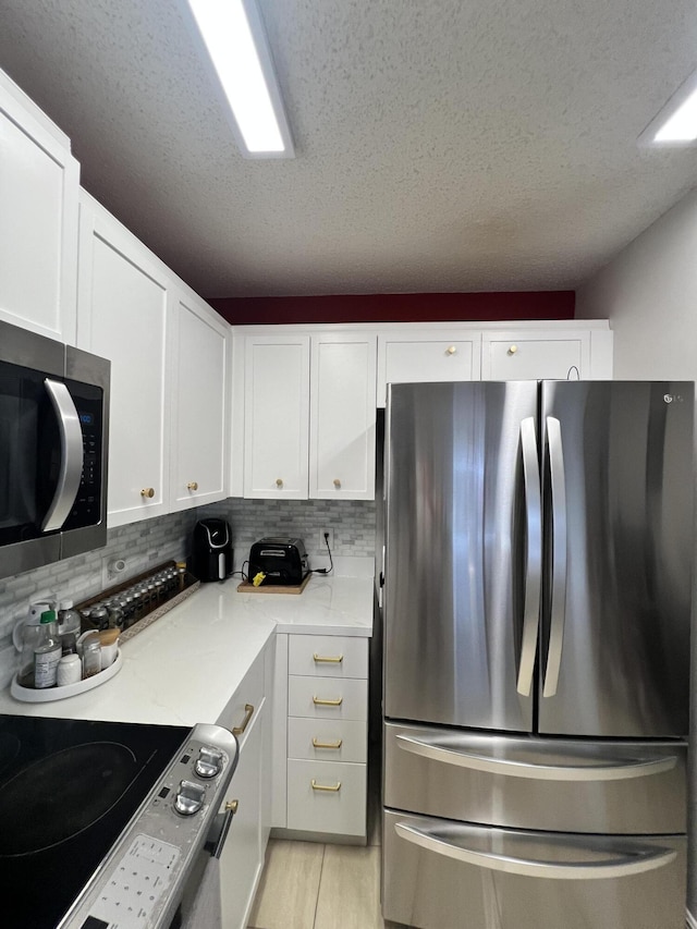 kitchen featuring white cabinets, decorative backsplash, appliances with stainless steel finishes, and a textured ceiling