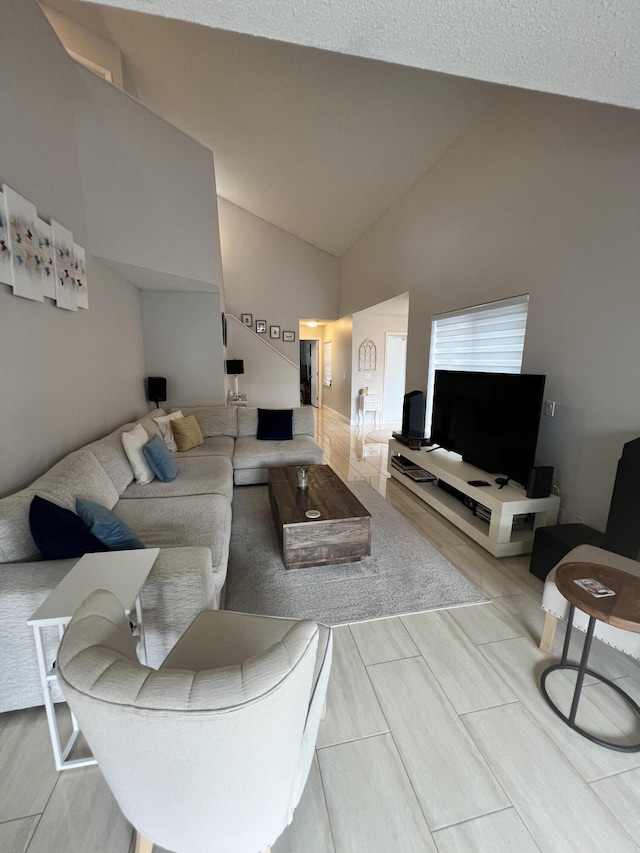 living room featuring high vaulted ceiling and a textured ceiling