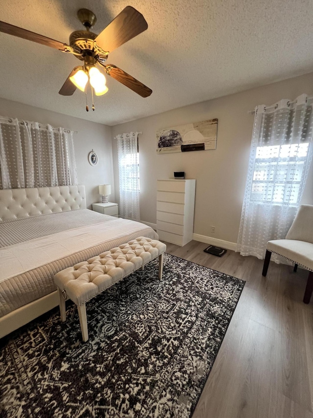 bedroom with ceiling fan, a textured ceiling, and hardwood / wood-style flooring