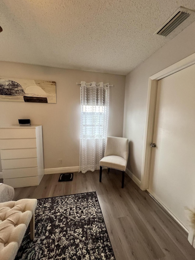 living area with a textured ceiling and hardwood / wood-style flooring