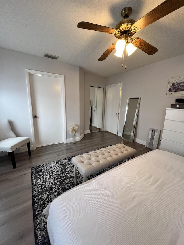 bedroom with ceiling fan, dark hardwood / wood-style flooring, and a textured ceiling