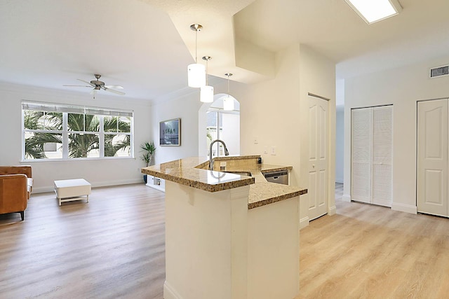 kitchen with decorative light fixtures, ceiling fan, light hardwood / wood-style floors, kitchen peninsula, and sink