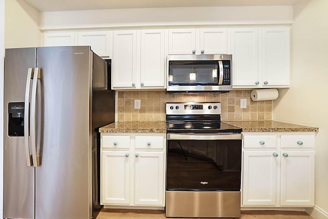 kitchen with backsplash, appliances with stainless steel finishes, stone counters, and white cabinetry