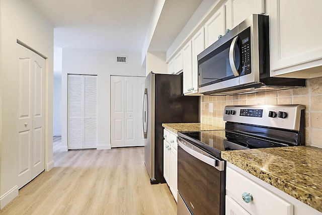 kitchen featuring white cabinets, appliances with stainless steel finishes, light stone counters, and light hardwood / wood-style floors