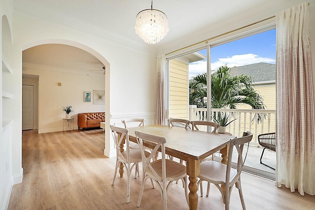 dining space with ceiling fan with notable chandelier, crown molding, and light hardwood / wood-style floors