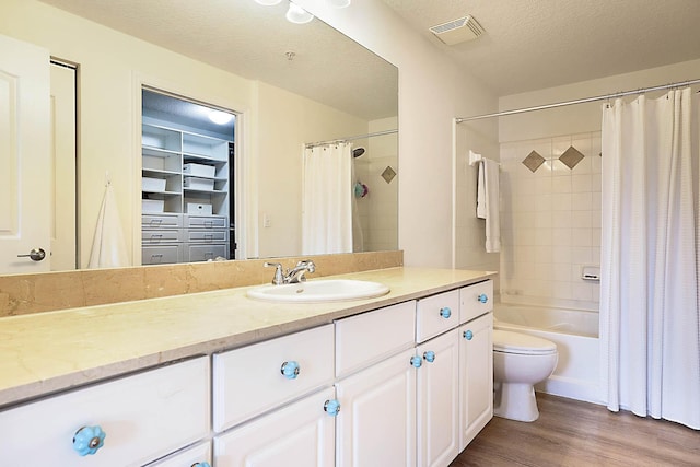 full bathroom with a textured ceiling, vanity, toilet, hardwood / wood-style flooring, and shower / bath combo