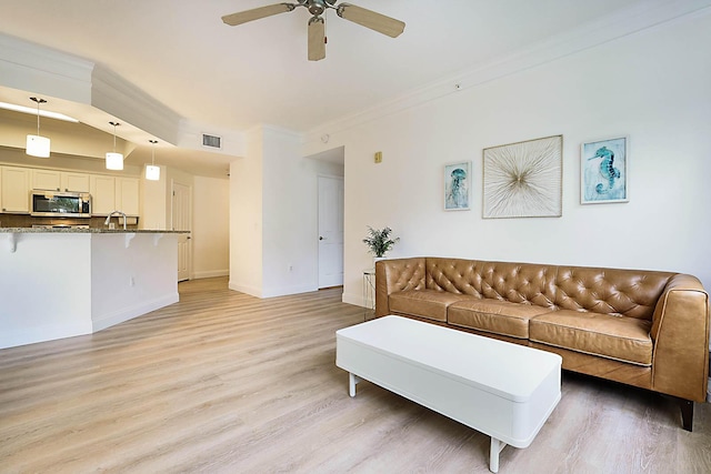 living room featuring ceiling fan, sink, crown molding, and light hardwood / wood-style floors