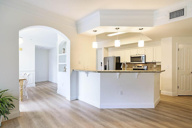 kitchen with stainless steel appliances, pendant lighting, white cabinets, and built in shelves