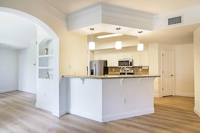 kitchen with pendant lighting, white cabinetry, stainless steel appliances, built in features, and kitchen peninsula