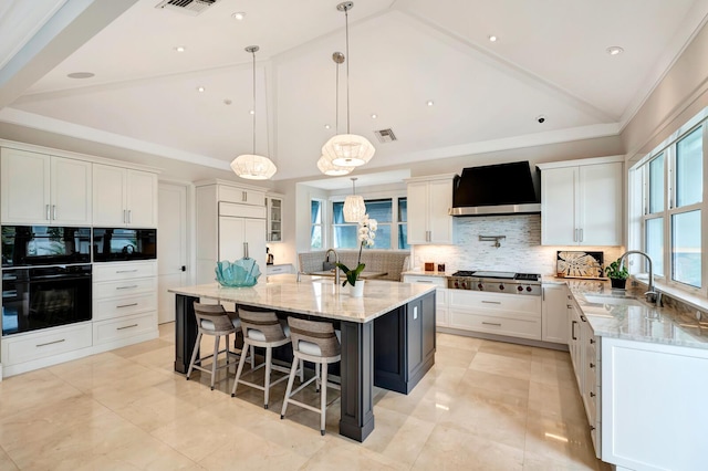 kitchen with white cabinets, pendant lighting, wall chimney exhaust hood, a spacious island, and sink