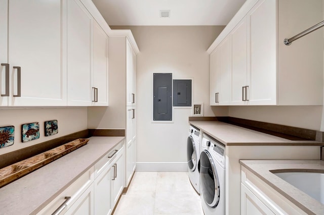 laundry room with electric panel, cabinets, washing machine and clothes dryer, and light tile patterned floors