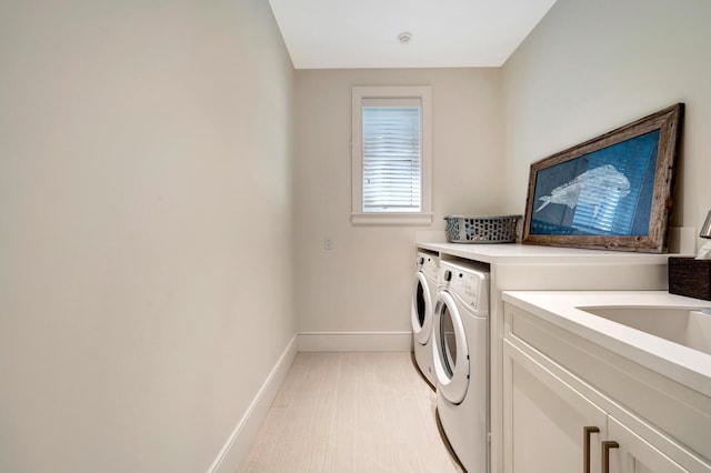 laundry area with separate washer and dryer, cabinets, and sink