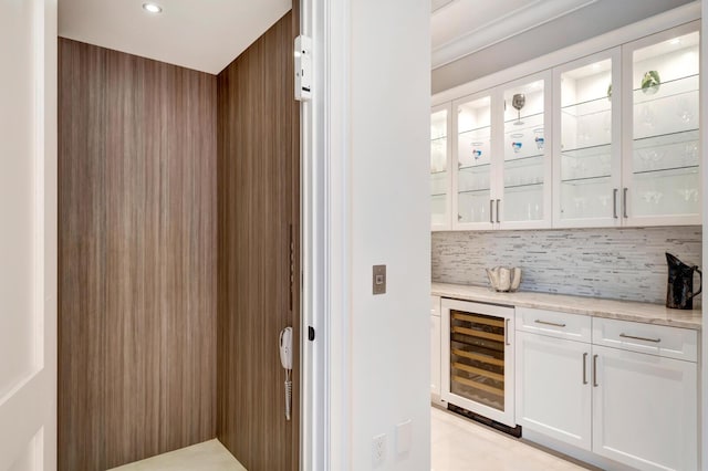 bar with white cabinets, backsplash, light stone countertops, elevator, and wine cooler