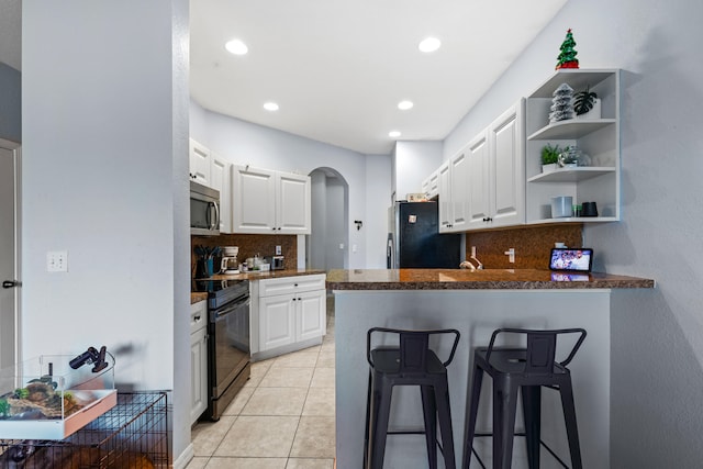 kitchen featuring appliances with stainless steel finishes, light tile patterned floors, white cabinets, and kitchen peninsula