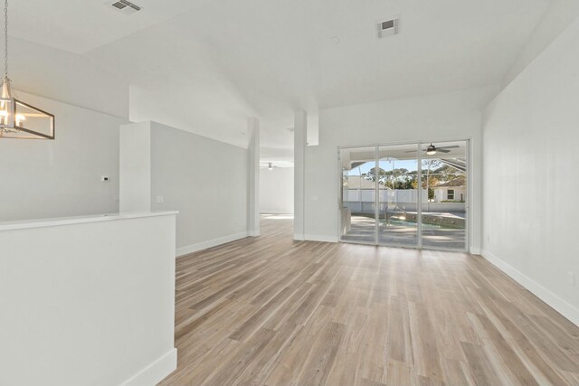 unfurnished living room with light wood-type flooring, vaulted ceiling, and french doors