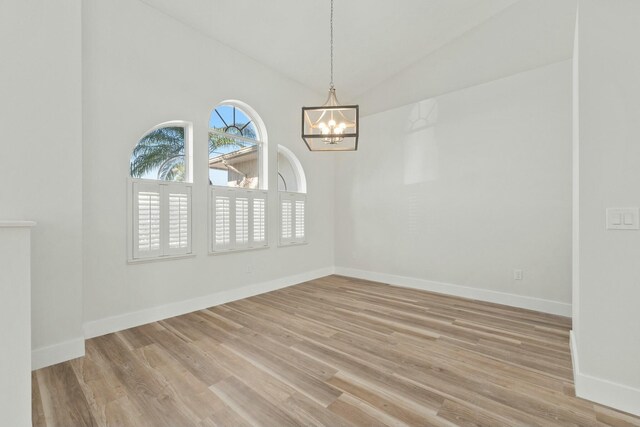 unfurnished living room with lofted ceiling, a chandelier, and light wood-type flooring