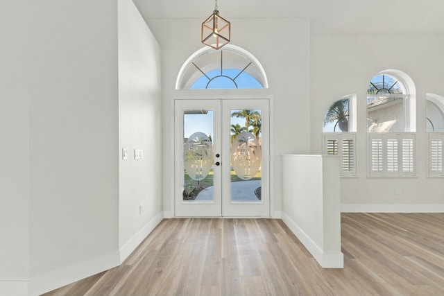 entryway with wood-type flooring, a towering ceiling, and french doors