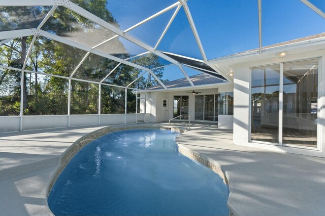 view of swimming pool featuring glass enclosure and a patio