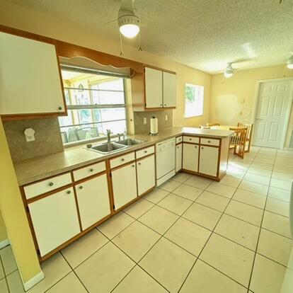 kitchen with white cabinets, dishwasher, sink, kitchen peninsula, and ceiling fan