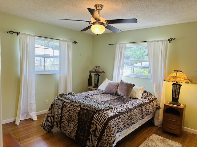 bedroom with ceiling fan, a textured ceiling, and dark hardwood / wood-style flooring