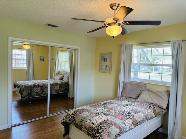 bedroom featuring ceiling fan, multiple windows, wood-type flooring, and a closet