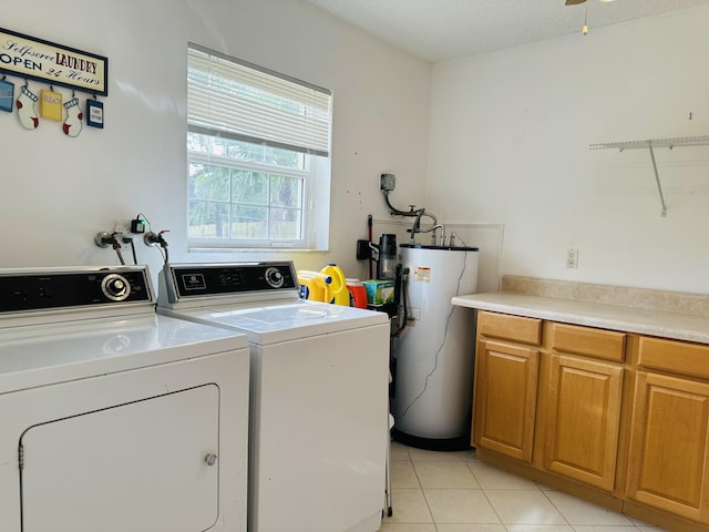 washroom featuring water heater, cabinets, light tile patterned floors, and washing machine and dryer