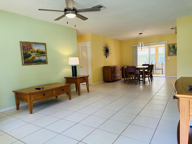 living room featuring ceiling fan, a textured ceiling, and light tile patterned floors