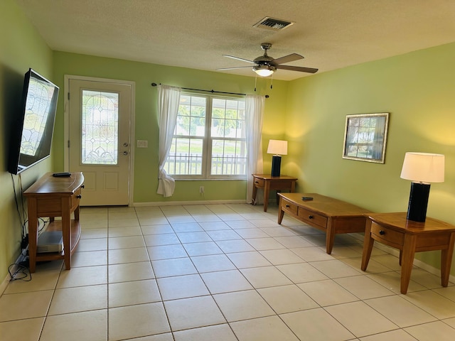 doorway with ceiling fan, a textured ceiling, and light tile patterned floors