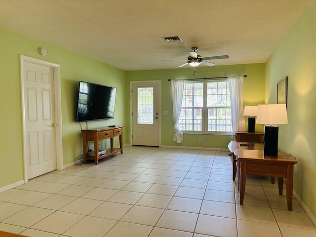 interior space with a textured ceiling, ceiling fan, and light tile patterned flooring