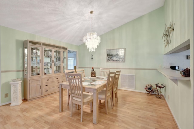 dining space with a textured ceiling, an inviting chandelier, and light hardwood / wood-style floors