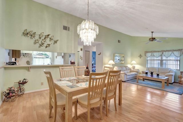 dining space with vaulted ceiling, a textured ceiling, light hardwood / wood-style floors, and ceiling fan with notable chandelier