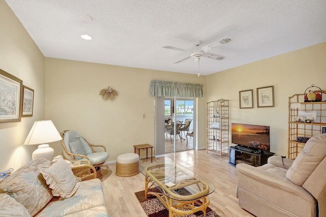 living room featuring a textured ceiling, ceiling fan, and light hardwood / wood-style floors