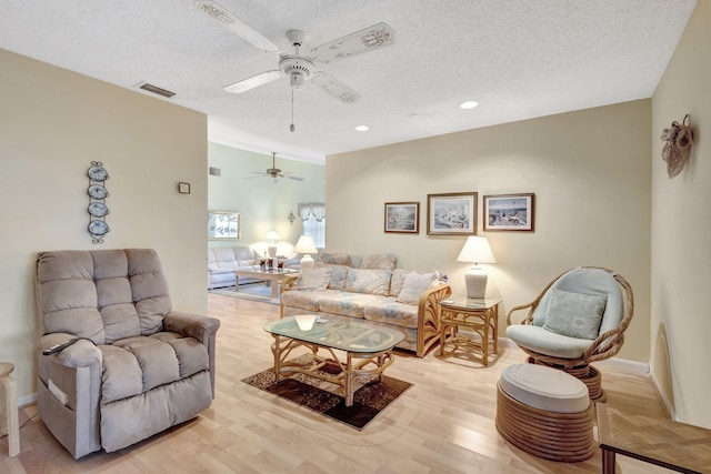 living room featuring ceiling fan, a textured ceiling, and light hardwood / wood-style flooring