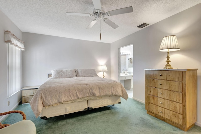 bedroom featuring ceiling fan, a textured ceiling, ensuite bath, and carpet flooring