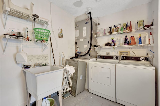 clothes washing area featuring washing machine and dryer, a textured ceiling, and sink