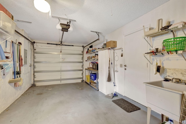 garage featuring sink, electric panel, and a garage door opener