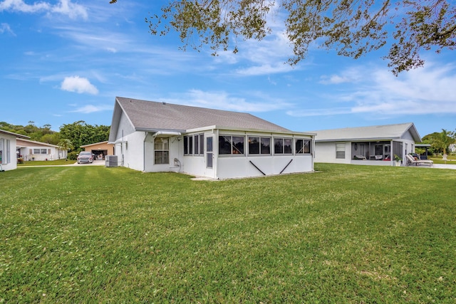 rear view of house featuring a sunroom, a lawn, and central air condition unit