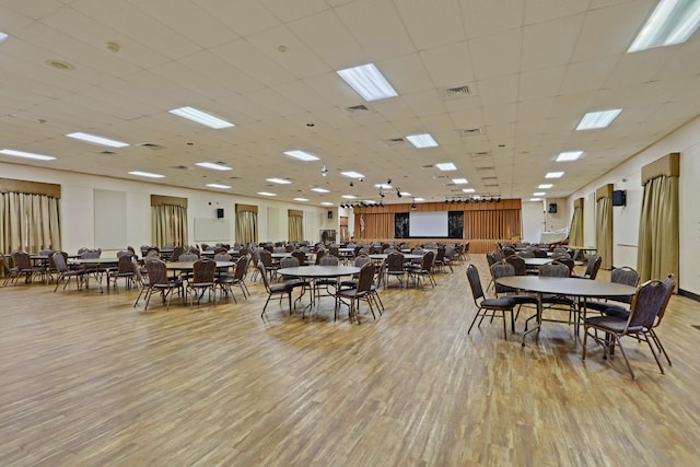 dining space featuring a drop ceiling and light hardwood / wood-style flooring