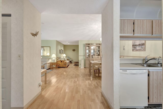 kitchen with light brown cabinetry, dishwasher, sink, and light hardwood / wood-style flooring