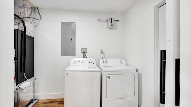 clothes washing area with electric panel, independent washer and dryer, and light hardwood / wood-style floors