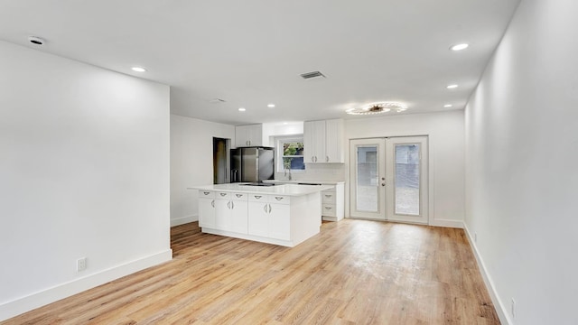 kitchen featuring white cabinets, fridge with ice dispenser, french doors, light hardwood / wood-style flooring, and a kitchen island