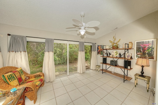 sitting room with a textured ceiling, ceiling fan, light tile patterned floors, and vaulted ceiling